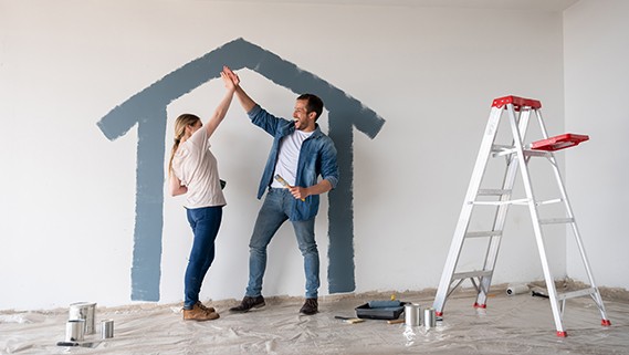 happy couple having fun painting their house together and giving a high-five